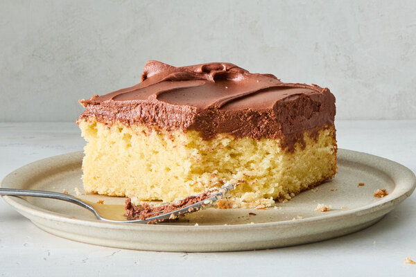 A side image of a piece of yellow cake topped with chocolate frosting.