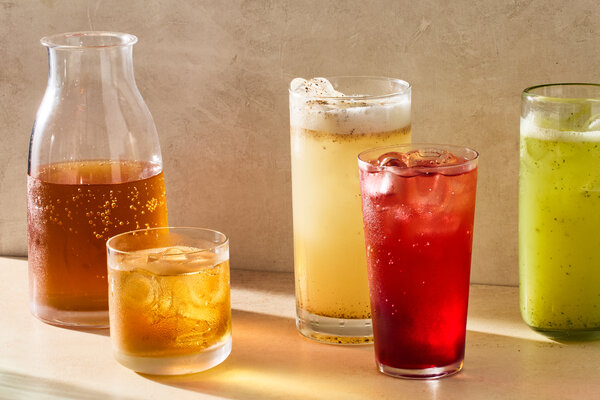 Glasses filled with red, yellow, tan and green beverages on ice.