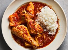 A Dutch oven filled with chicken and kimchi parts next to a bowl of white rice. 