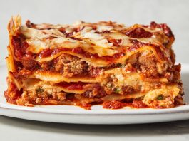 A piece of lasagna is photographed from the side to show its many layers.