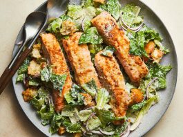 A bed of arugula topped with shredded chicken and a generous layer of roasted chickpeas. Halved cherry tomatoes and dark olives provide pops of red and purple. 