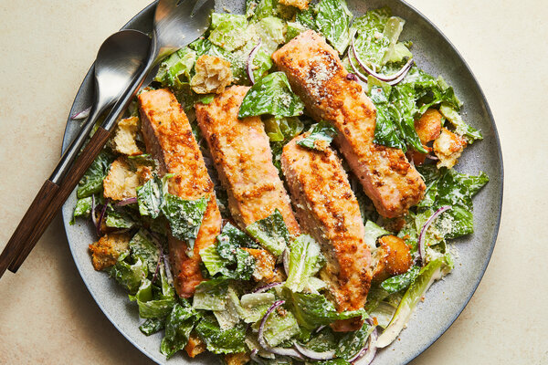 A bed of arugula topped with shredded chicken and a generous layer of roasted chickpeas. Halved cherry tomatoes and dark olives provide pops of red and purple. 