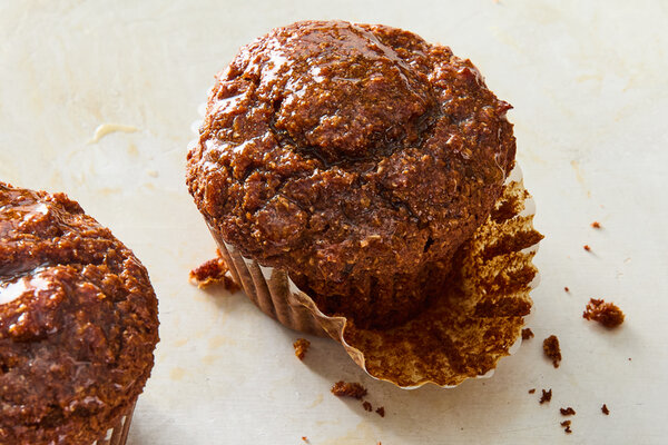 A group of bran muffins with one torn in half toward the center.