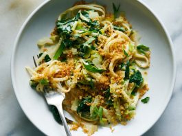 Creamy Swiss chard pasta with leeks, tarragon and lemon zest is shown in a white plate with a fork.