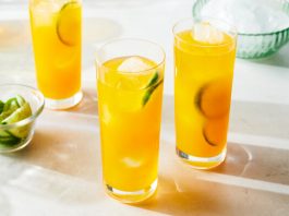Two tall glasses of a golden juice. 