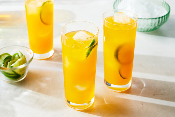 Two tall glasses of a golden juice. 