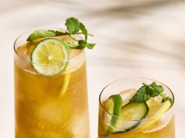 Two tall, clear glasses of a Pimm’s cup photographed at an angle.