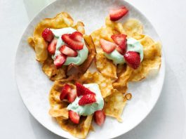 An overhead image of crepes topped with whipped cream and strawberries.