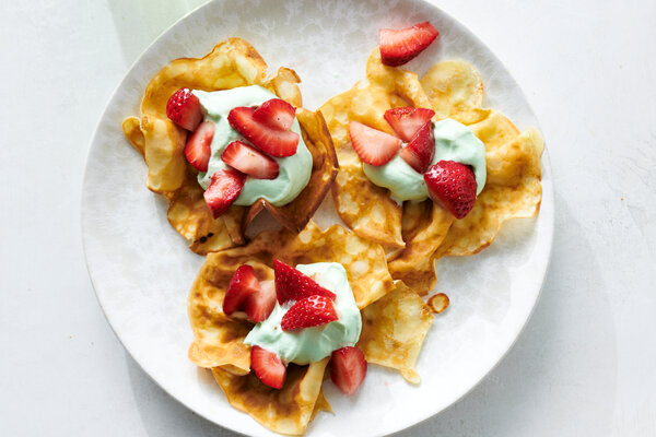 An overhead image of crepes topped with whipped cream and strawberries.