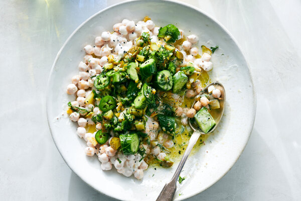 An overhead image of chickpeas and cucumbers in a creamy sauce.