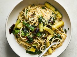 An overhead image of pasta surrounded by zucchini batons in a bowl.