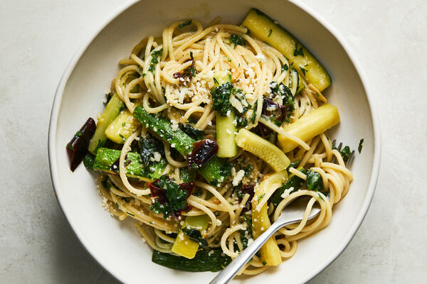 An overhead image of pasta surrounded by zucchini batons in a bowl.