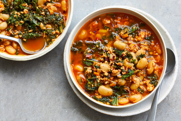 An overhead image of two soup bowls filled with beans and greens.