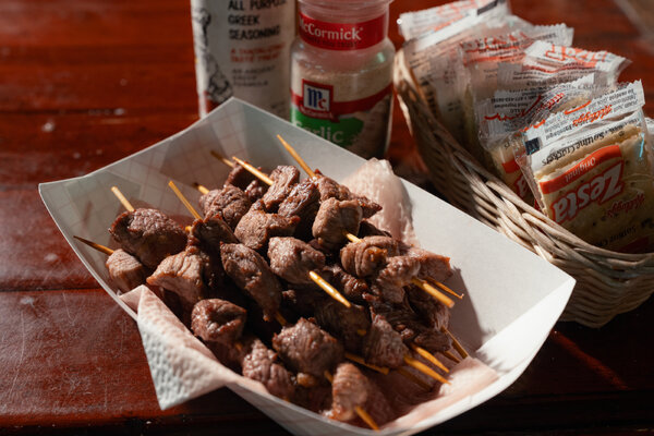 Skewers in a paper basket next to Saltine crackers, garlic salt and Greek seasoning.