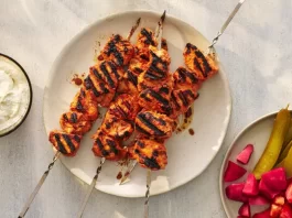 An overhead image of shrimp kebabs and shish tawook on platters.